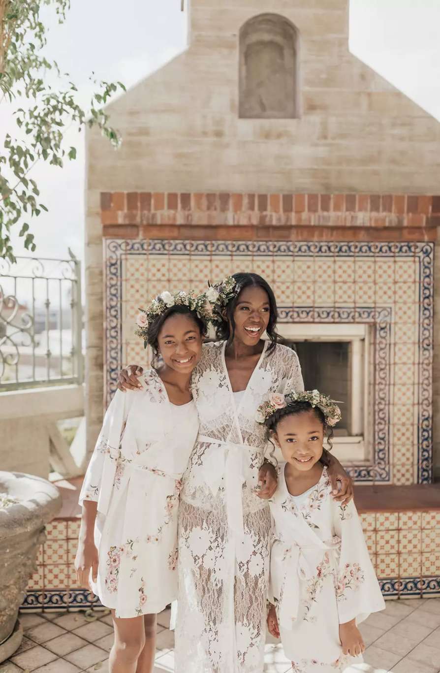 Bride and flower girls wearing white robes while getting ready for the wedding