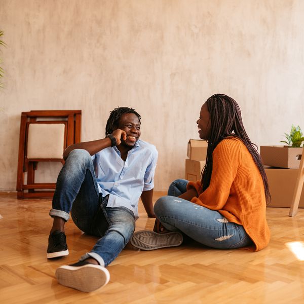 young couple talking while sitting on floor of their new apartment