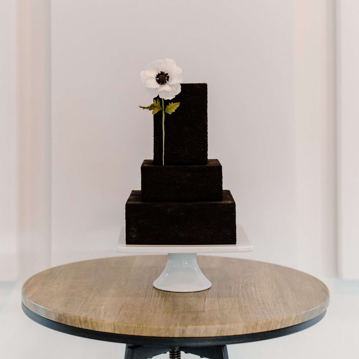 Three-tier black cake with anemone flower