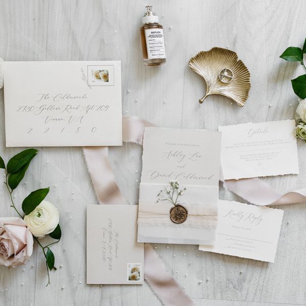 neutral wedding invitation suite with cream paper with deckle edges, pink ribbon, and gold wax seal