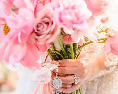 Bride holding a wedding bouquet of pink flowers with charms