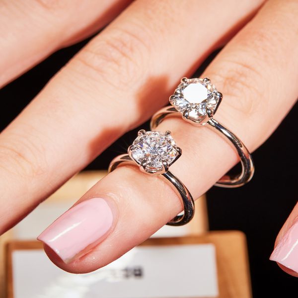 Finger wearing two diamond solitaire rings