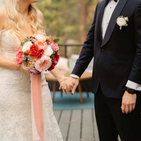 Lower Half of Bride and Groom Holding Hands on Outdoor Deck