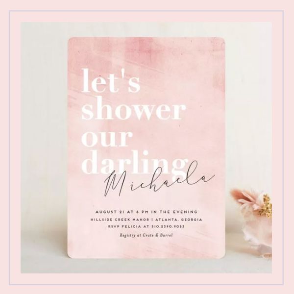 A bridal shower invitation on an off-white background with a pink border