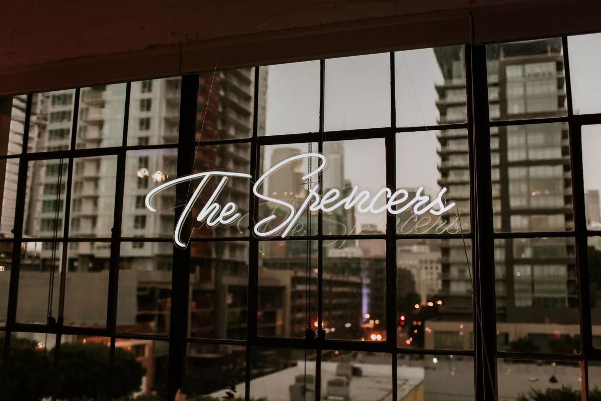 White neon sign that says "The Spencers" against black windows