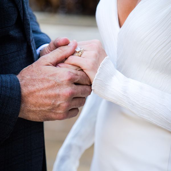 Closeup of Bride and Groom Holding Hands With Diamond Ring on Display