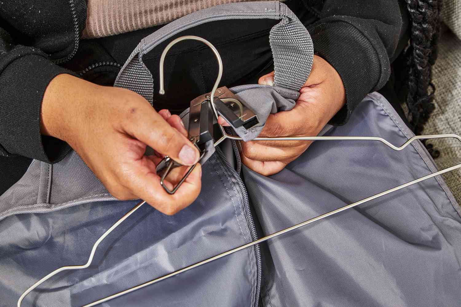 Closeup of hands placing a garment hanger into the WallyBags Deluxe Garment Bag