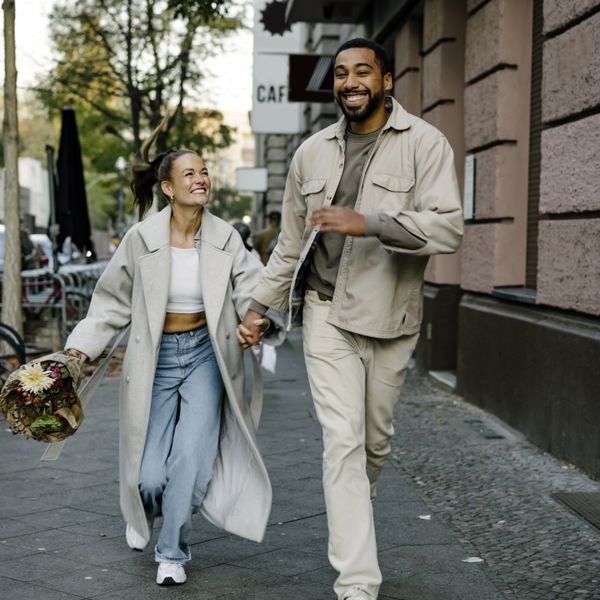 Couple holding hands and smiling while walking down the street