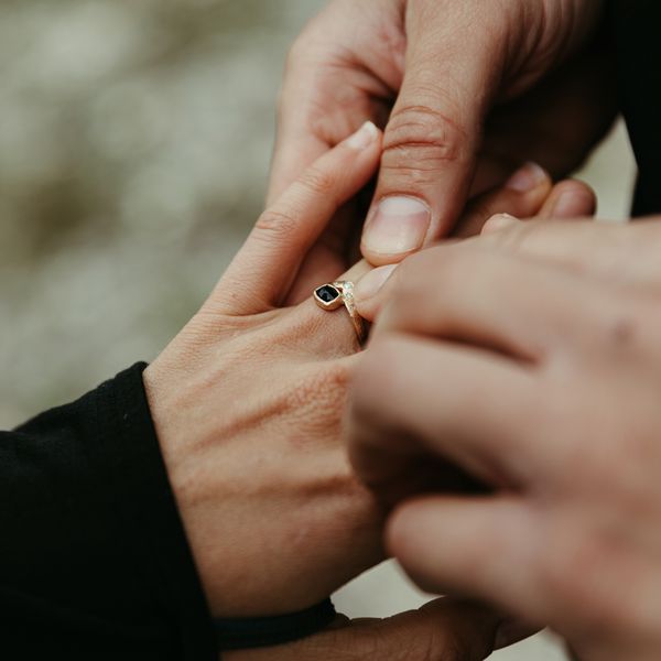 Man puts custom engagement ring on woman's finger post proposal