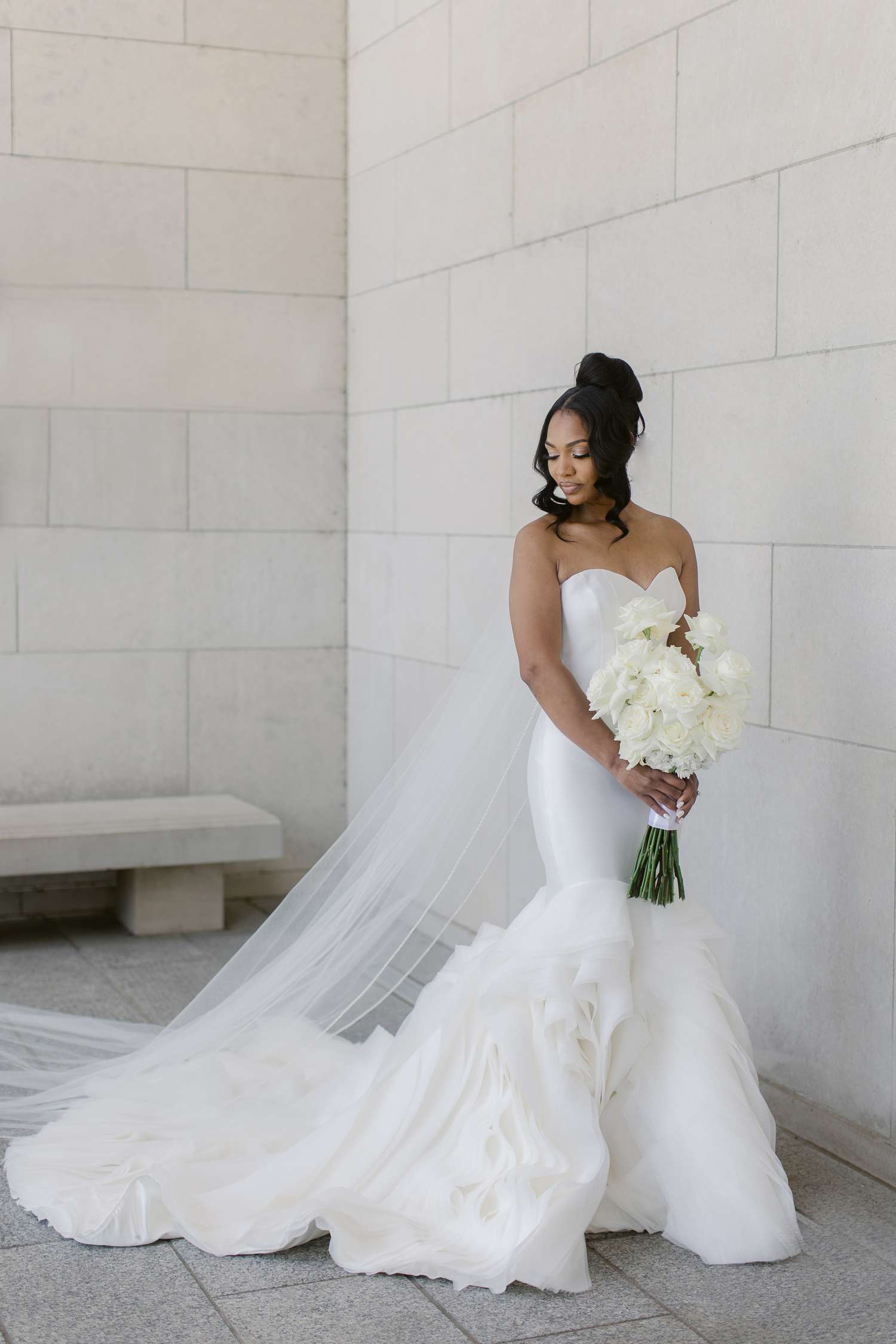 bride in strapless mermaid gown holding a wedding bouquet of white flowers