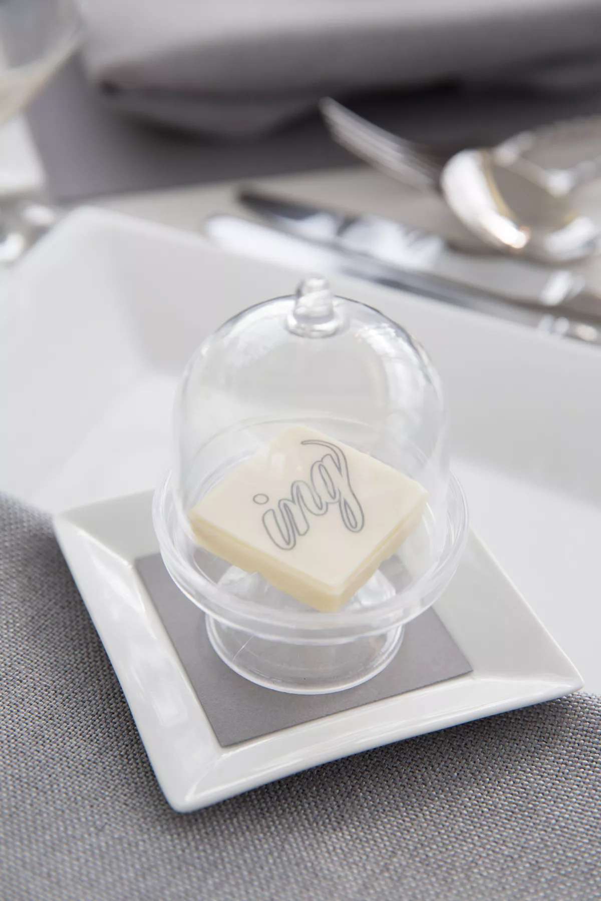 Back and white chocolates with monogram in glass cloche on plate