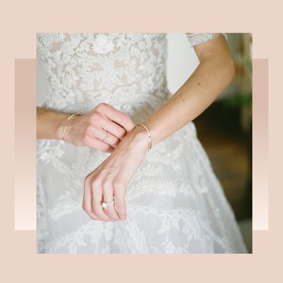 Bride adjusting bracelet while wearing wedding dress and engagement ring