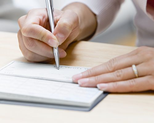 Woman Writing a Wedding Check on Wood Table