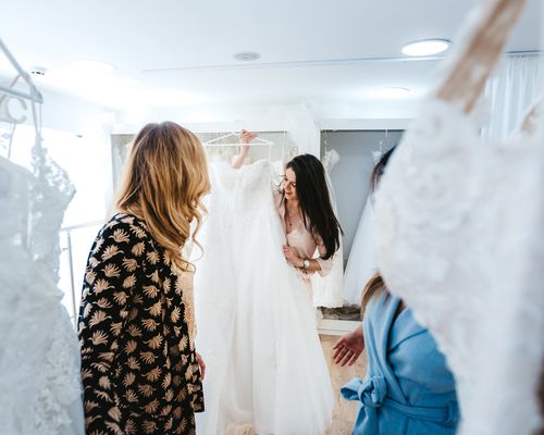 Bride and Two Bridesmaids Looking at Wedding Dress During Shopping Appointment