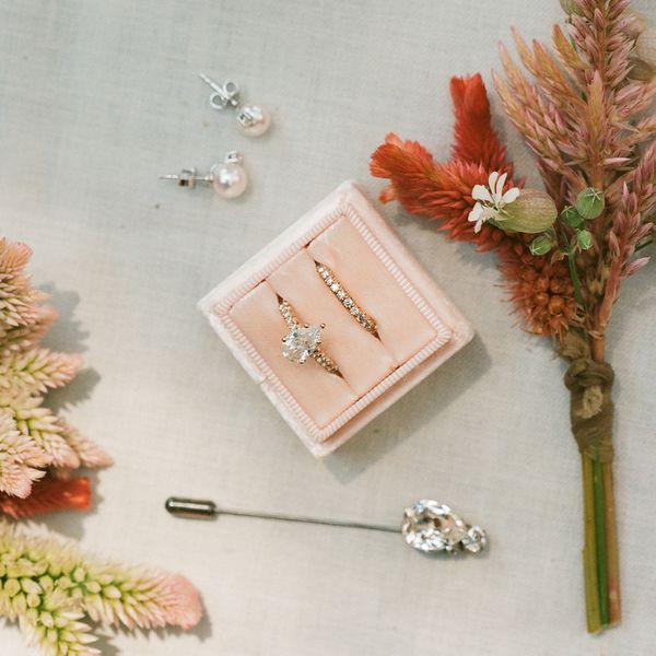 a still shot of pearl earrings, a diamond engagement ring and wedding band, and a diamond hair pin