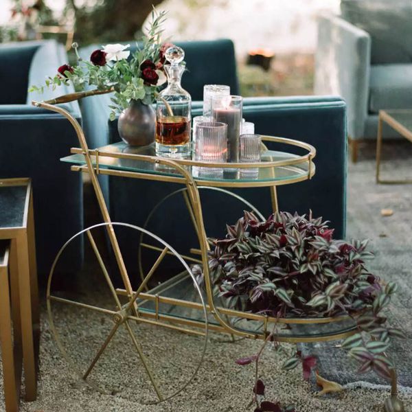 glass bar cart with drinks, glasses, and flora