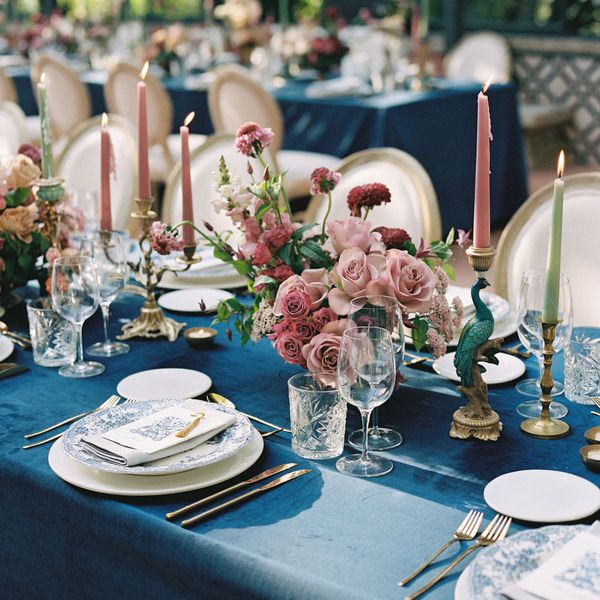 dusty rose wedding centerpiece next to pink and green taper candles and blue tablecloth