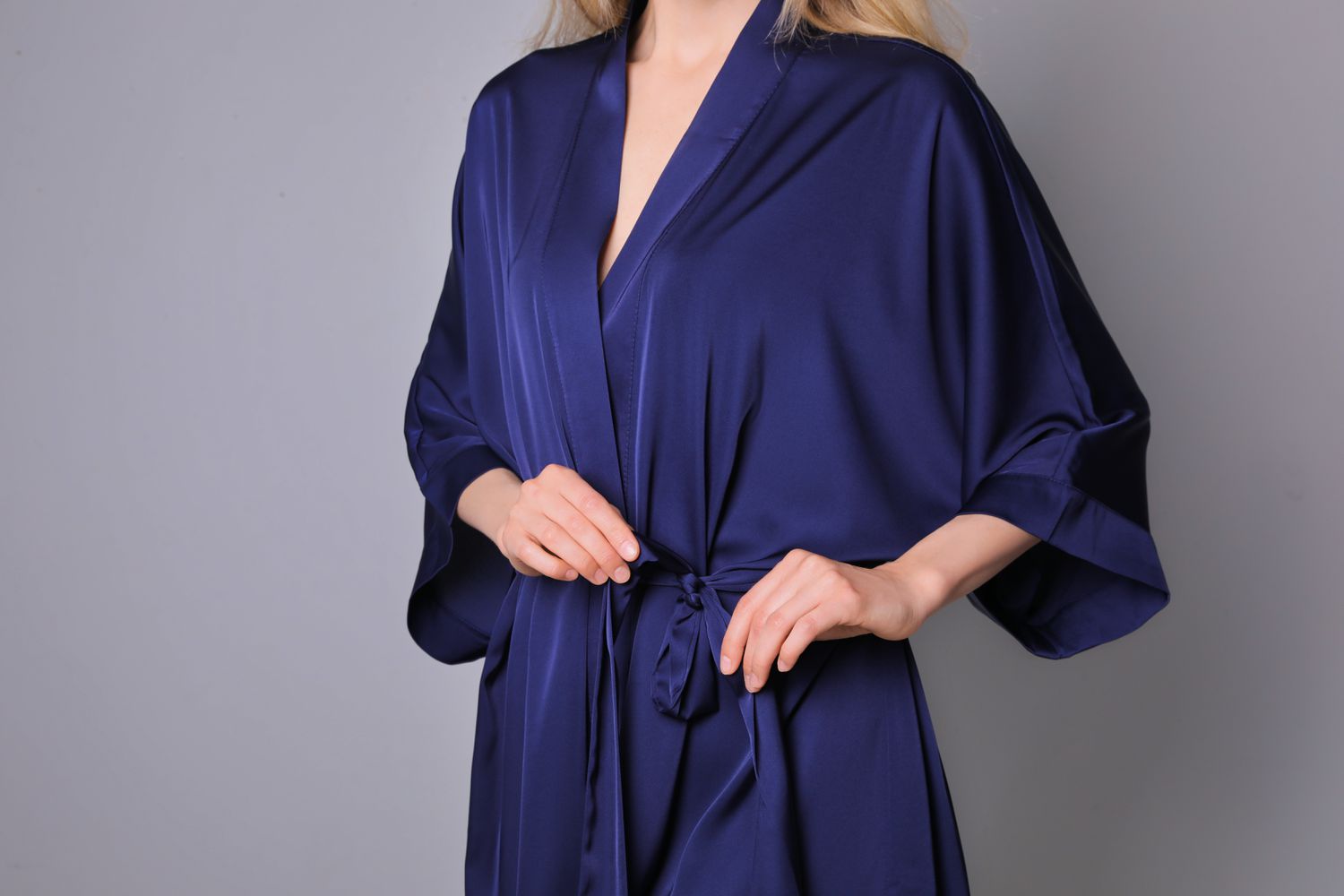 Woman tying a navy blue silk robe