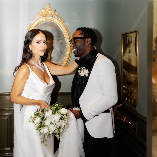 Bride in Wedding Dress Holding White Bouquet Posing With Groom in Black and White Tuxedo in Elevator 