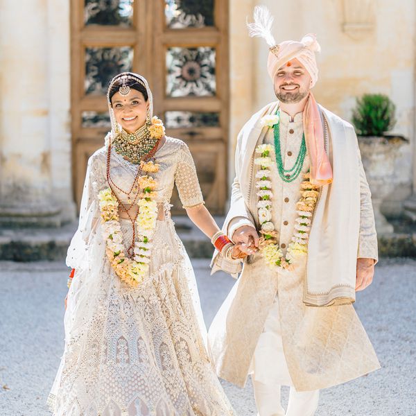 bride and groom in traditional Indian wedding attire holding hands smiling