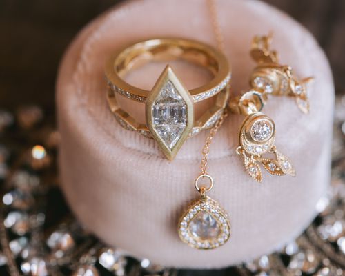 a marquise cut gold engagement ring photographed with gold and diamond earrings and a necklace