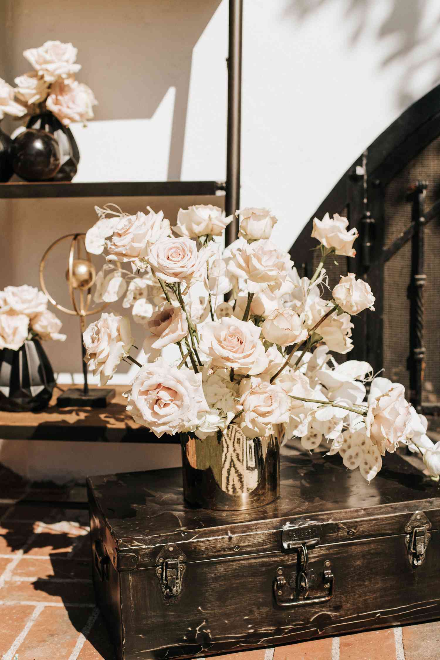 Black trunk with white flower arrangement in gold vase