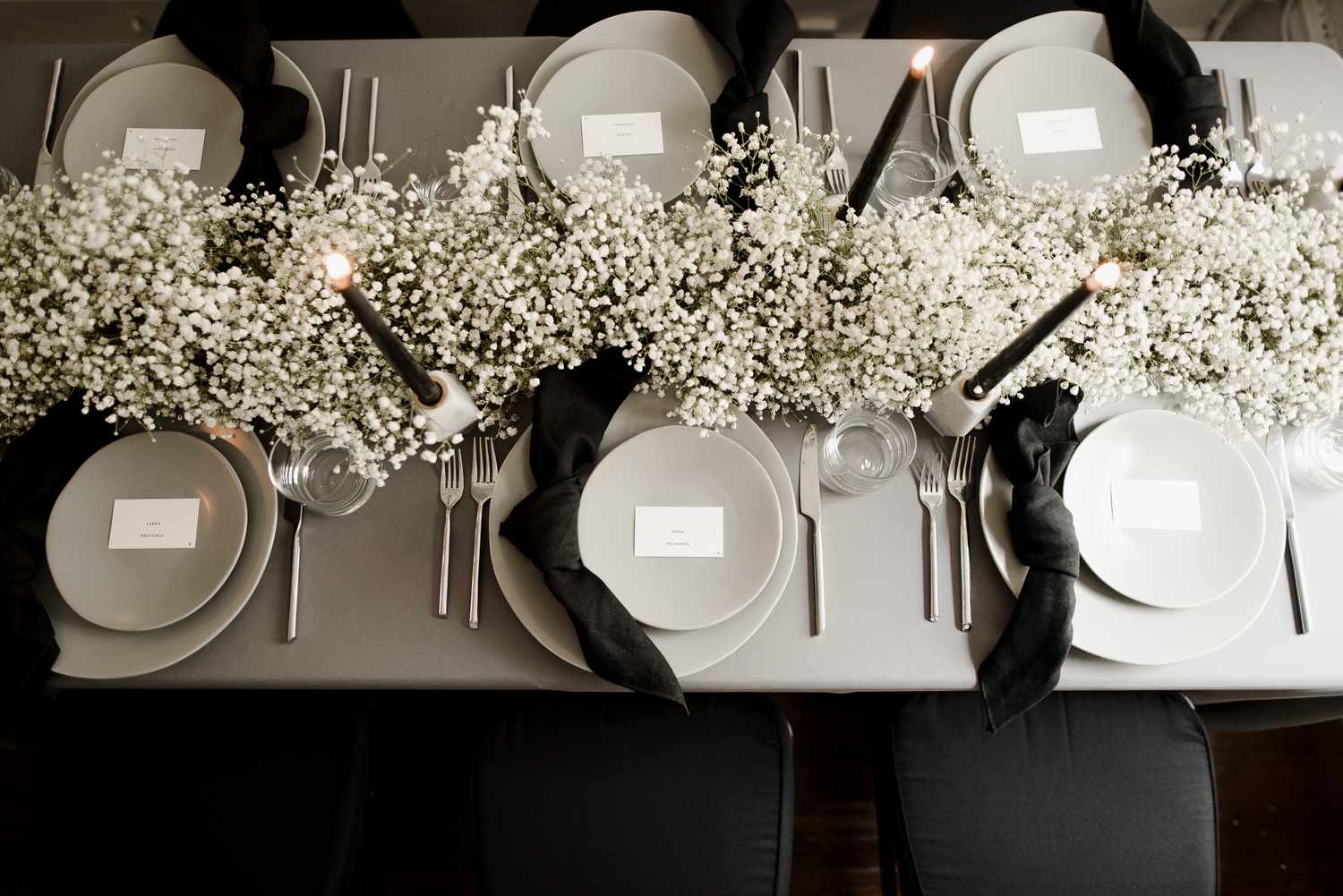 Baby's breath centerpiece on table with black napkins and black taper candles