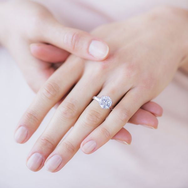 close up of a woman's hand with a diamond engagement ring