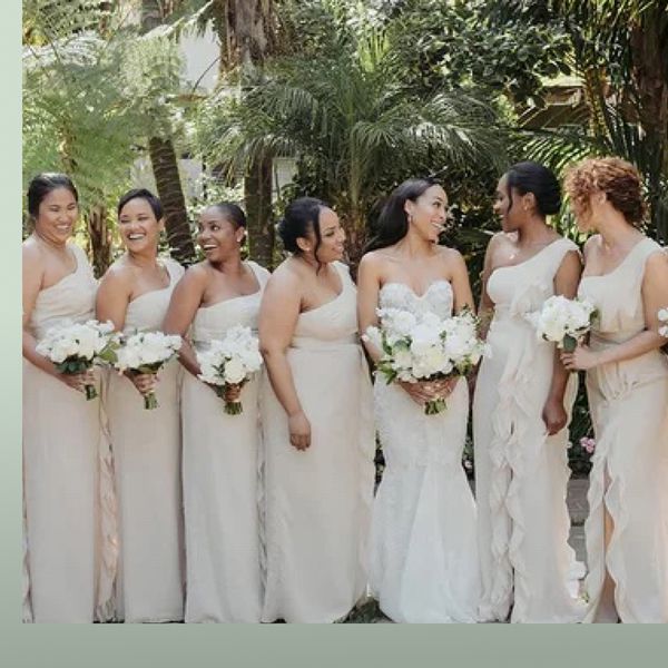 Brides standing with bridesmaids in front of palm trees