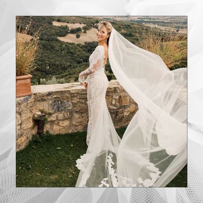 A smiling bride overlooking a beautiful landscape; bride wears a white wedding dress and a long flowing veil