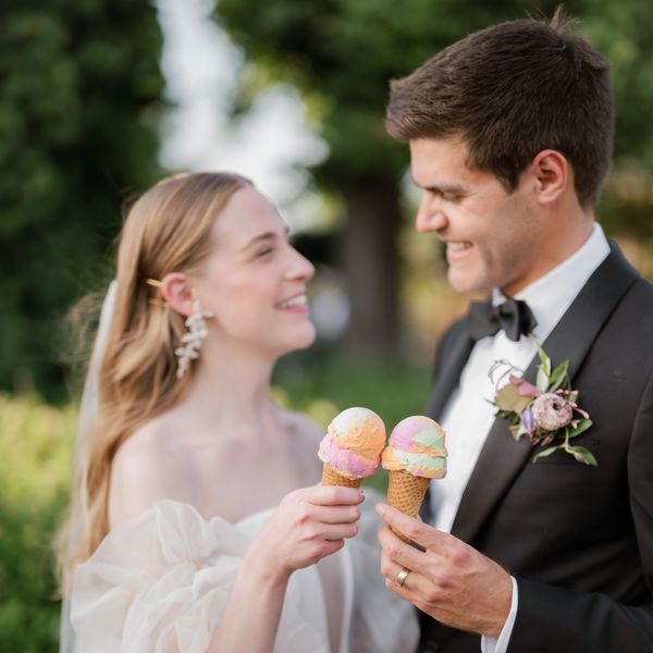 Bride in Wedding Dress With Voluminous Sleeves and Groom in Black Tuxedo Holding Ice Cream Cones 