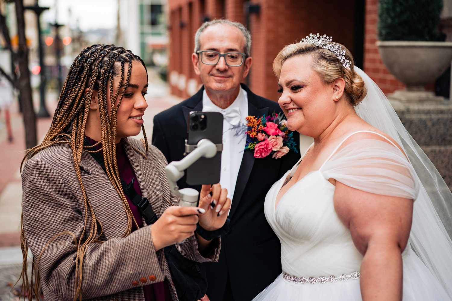 A wedding social content creator looking at an iphone with a bride and groom