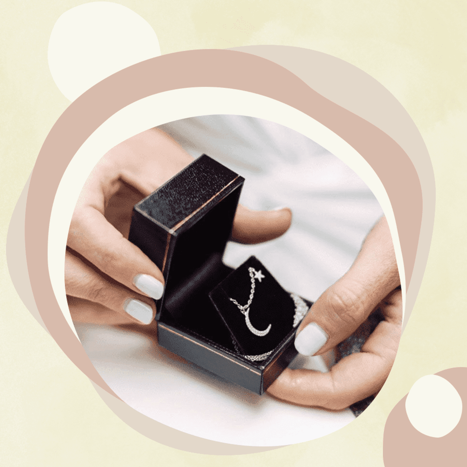 A black necklace box containing a delicate silver chain necklace with moon and star charms.