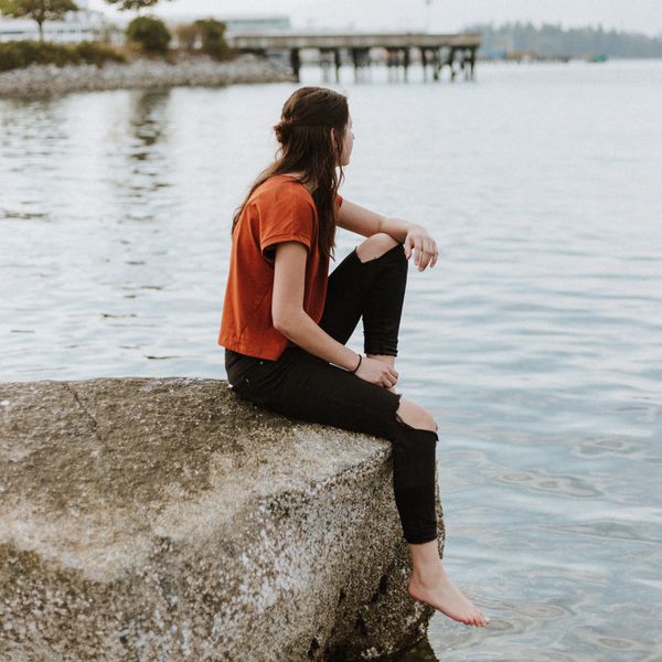 woman sitting alone looking out at water