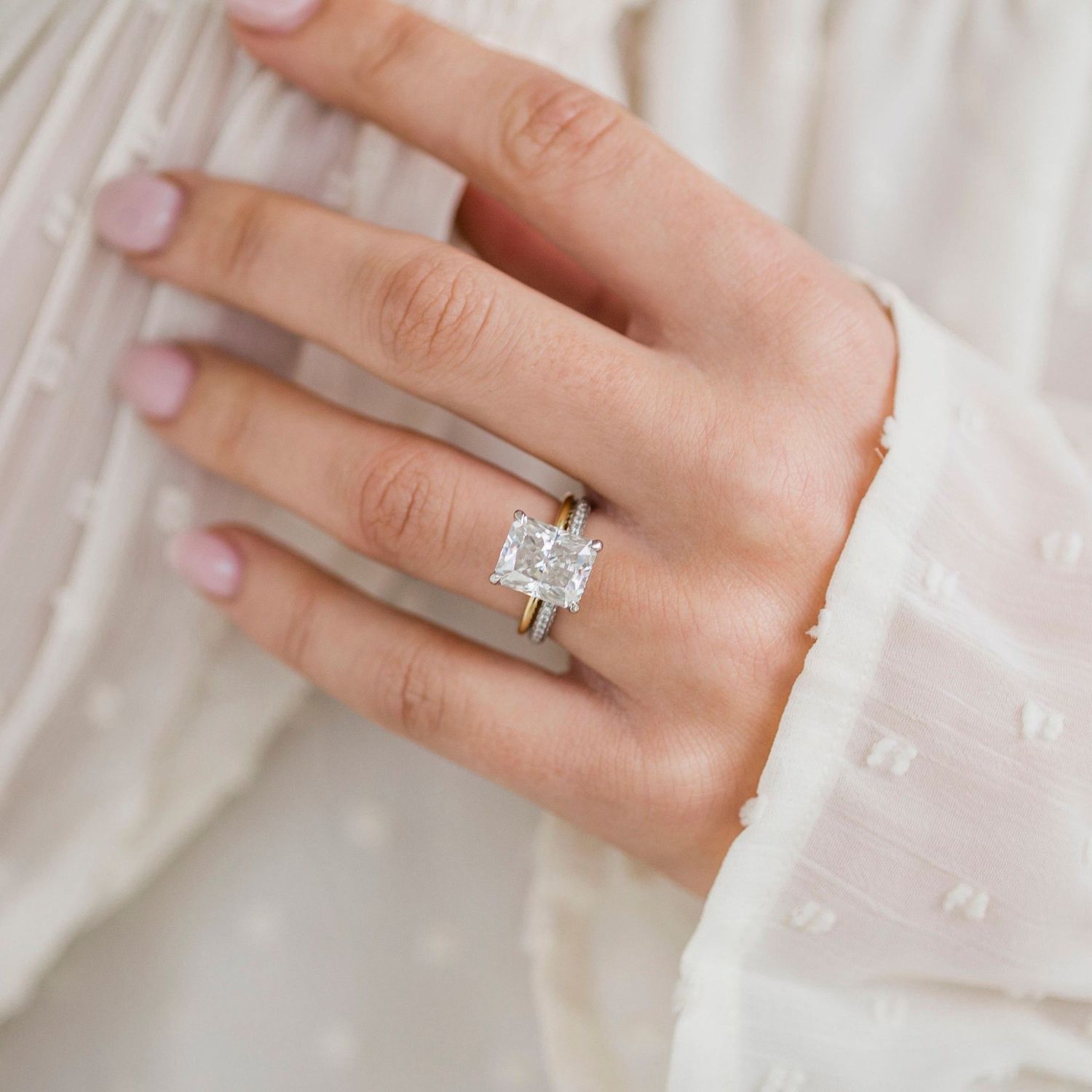 Radiant-cut diamond ring on hand with gold band