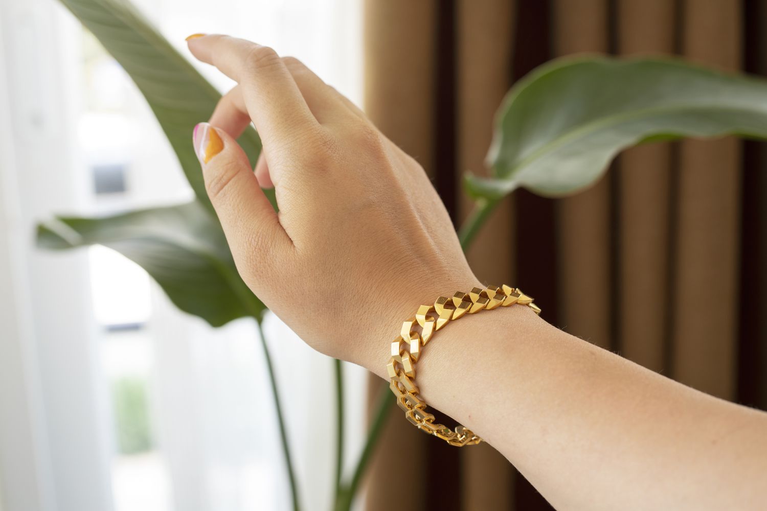 A woman stretching out her hand, showing a gold chain bangle on her wrist