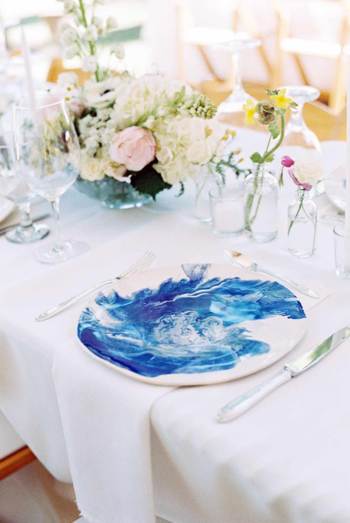 Handmade watercolor plates on wedding tablescape with bud vases and floral arrangements