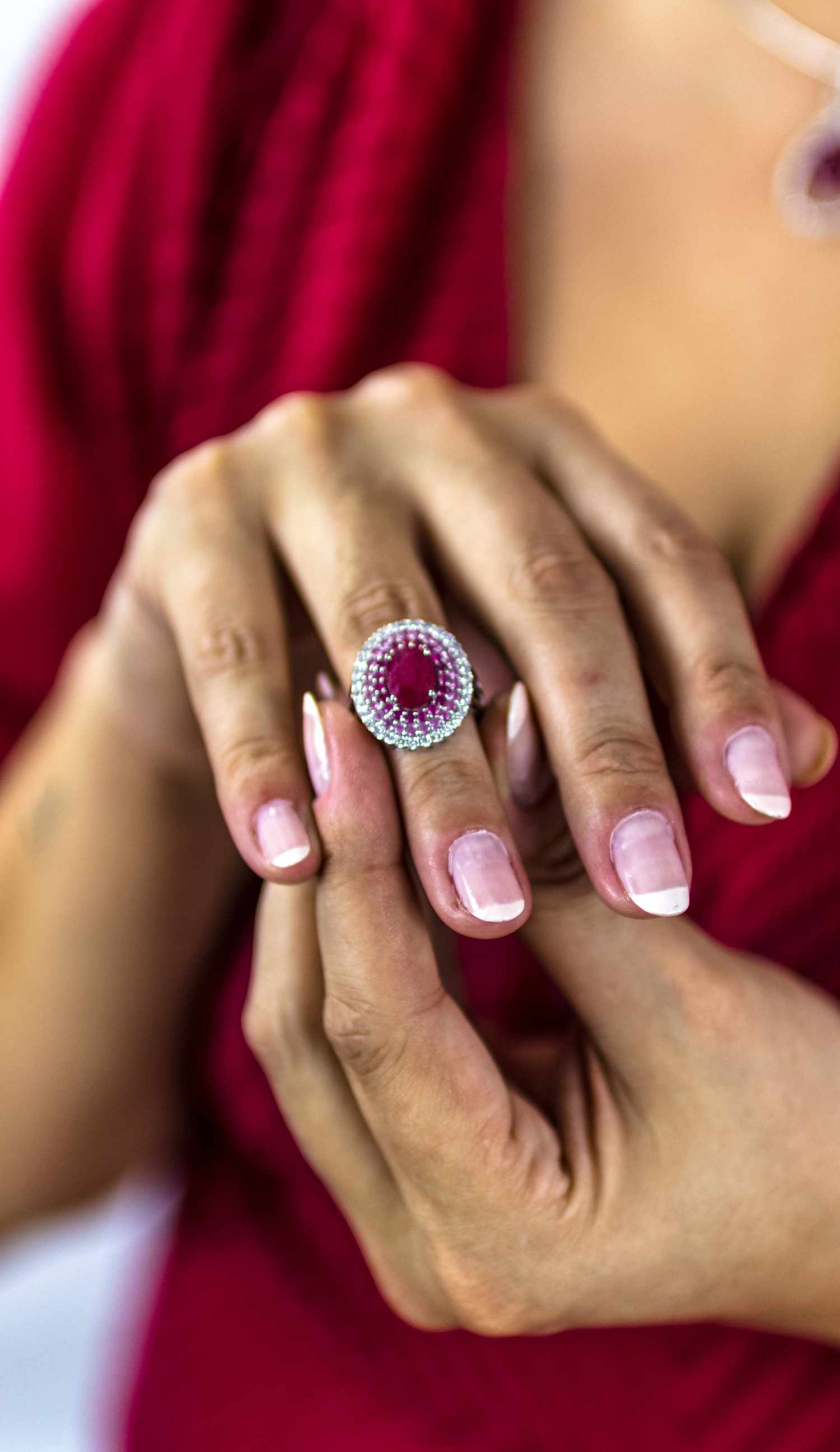 A woman putting a ruby and diamond ring on her ring finger