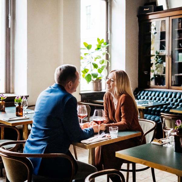 40s Couple Holding Hands While Sitting at a Table on a Date in a Restaurant