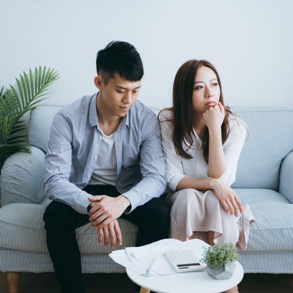 Couple sitting on a couch, with the man looking down and the woman looking away