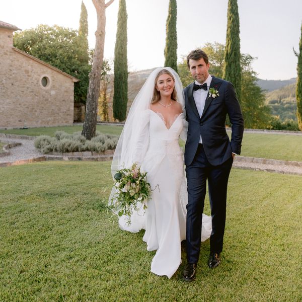 Bride in Wedding Dress and Veil Posing With Groom in Black Tuxedo in Garden