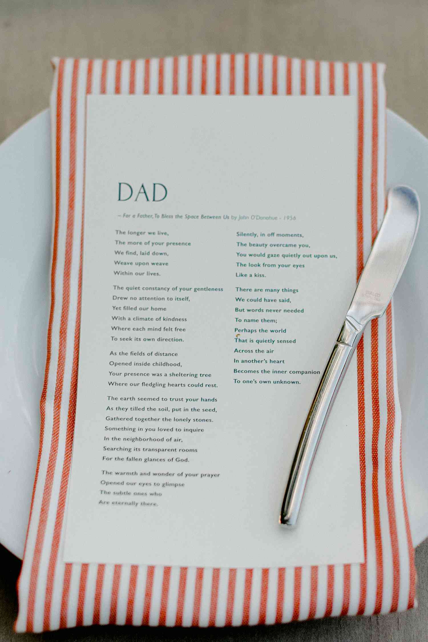 Wedding place setting with striped orange napkin and personalized poem selection