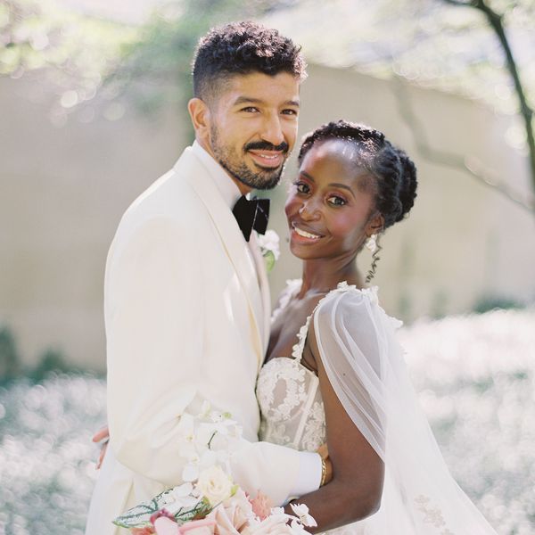 Groom in White Tuxedo and Bride in Lace Wedding Dress in Floral Field