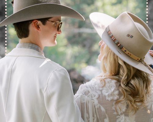 Brides couple wearing cowboy hats looking at eachother