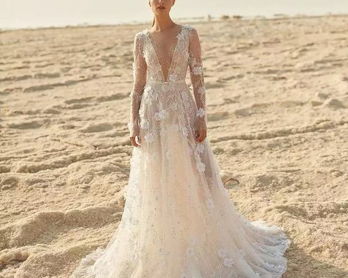 A woman in a beaded wedding dress standing in a sandy landscape