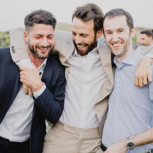 three men laughing and hugging in cocktail attire