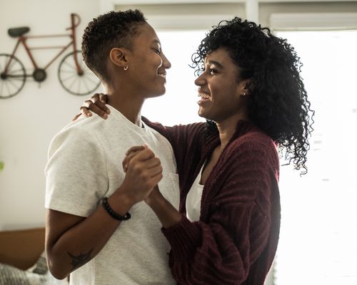 Happy Young Couple Holding Hands and Smiling in Home