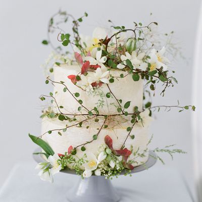 Fall white wedding cake with greenery, white flowers, and red leaves