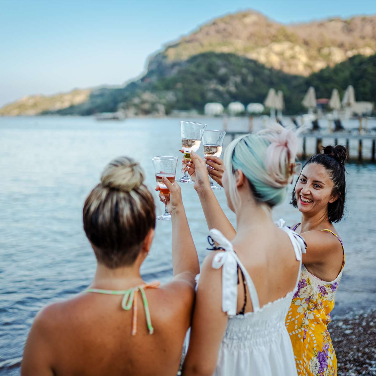 women on a bachelorette party toasting wine glasses by a lake