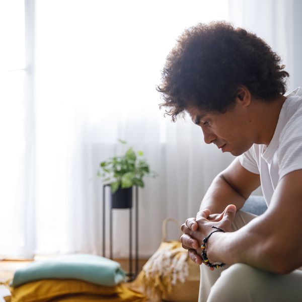 A distressed man sits on the couch thinking.